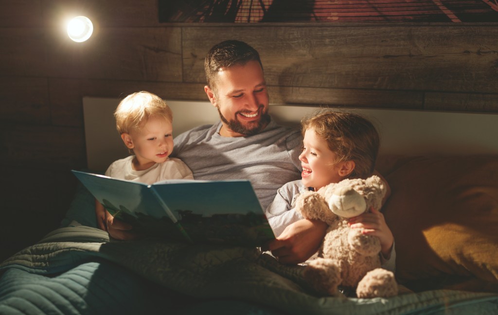 father reading story to two children in bed